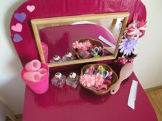 a pink table topped with a mirror and bowls filled with candy