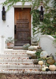 pumpkins and gourds are sitting on the steps in front of a house