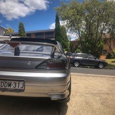 the back end of a silver car parked in front of a house