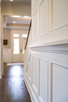 an empty hallway with white walls and wood flooring is seen from the entrance way