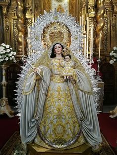 a statue of the virgin mary and child jesus in front of an ornate gold throne