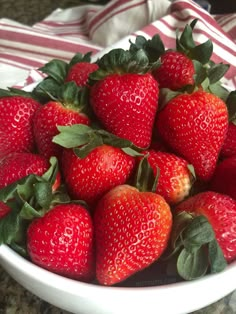 a white bowl filled with lots of ripe strawberries