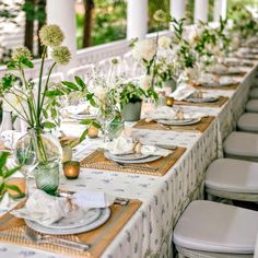 a long table set up with place settings and flowers in vases on the tables