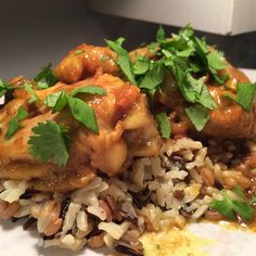 chicken and rice with cilantro garnishes on a white plate, ready to be eaten