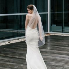 a woman in a wedding dress is standing on a wooden floor with her back to the camera