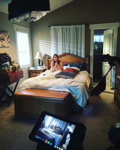 a woman is sitting on her bed in the middle of a room with an ipad