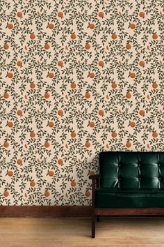 a green couch sitting in front of a wall with oranges on it