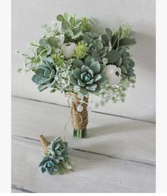 a bridal bouquet with succulents and greenery on a wooden table