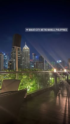 the city skyline is lit up at night from an outdoor deck with wicker chairs