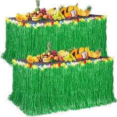 an arrangement of fruits and vegetables are arranged on a grass table runner for a tropical themed birthday party