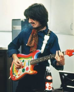 a man holding an electric guitar in his hand and wearing a scarf around his neck