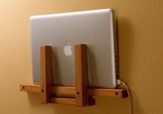 an apple laptop on a wooden stand attached to a wall