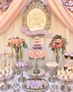 a table topped with lots of cakes and cupcakes next to a mirror on the wall