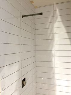 an empty white shower stall with no curtain on the wall and toilet in the corner