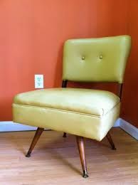 a yellow chair sitting on top of a hard wood floor next to an orange wall