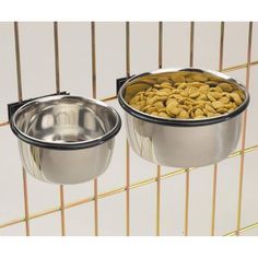 two metal bowls with food in them hanging from the side of a wire fence on top of each other