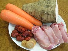 a plate with carrots, almonds and meat on it next to a root