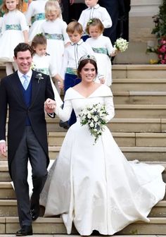 the bride and groom are walking down the steps with other people in white dresses behind them