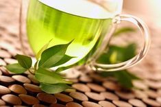 a glass cup filled with green tea sitting on top of a table