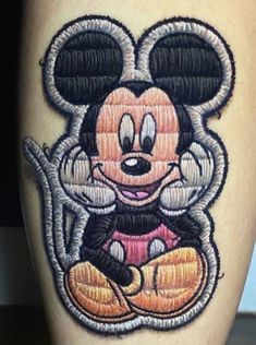 a mickey mouse tattoo on the leg