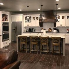 a large kitchen with white cabinets and wooden floors