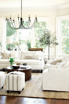 a living room filled with white furniture and a chandelier hanging from the ceiling