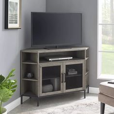 a flat screen tv sitting on top of a wooden entertainment center next to a window