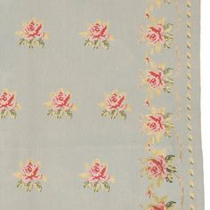 a blue rug with pink and yellow flowers on it's border, in front of a white background