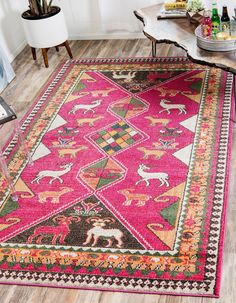 a pink rug with animals on it in the middle of a living room next to a coffee table