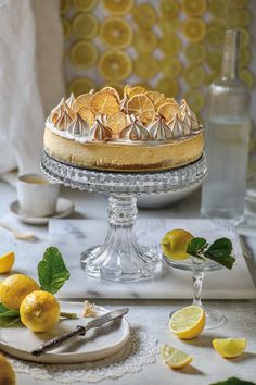 a cake with lemons on it sitting on a table next to other food and utensils