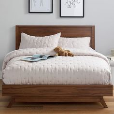 a bed with two pictures on the wall above it and a teddy bear laying on top