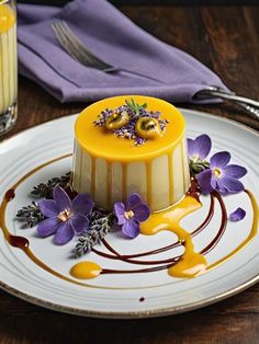 a yellow cake sitting on top of a white plate next to a glass of orange juice