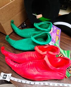 three plastic shoes sitting on top of a wooden floor next to a tape measure ruler