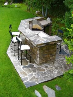 an outdoor grill with chairs and tables in the grass