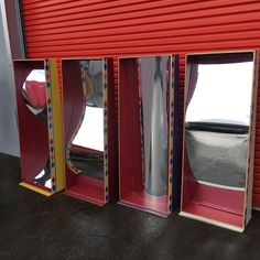 three different colored windows in front of a red garage door with the reflection of a car