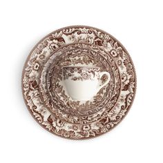 the brown and white cup is on top of the saucer, which has an ornate design