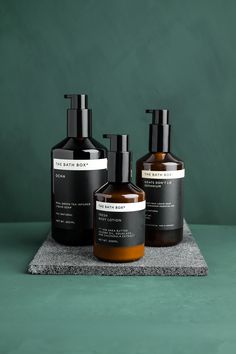 three bottles of hand soap and lotion sitting on a countertop against a green background