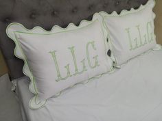 two pillows that are on top of a bed with white sheets and green trimmings