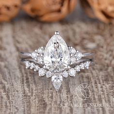 an engagement ring with a pear shaped diamond center surrounded by smaller round brilliant cut diamonds