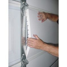 two hands are holding onto the side of a door with a ruler attached to it