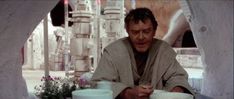 a man sitting at a table eating food with cups and saucers in front of him