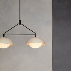 three lights hanging from a ceiling fixture in a room with concrete walls and flooring