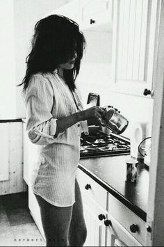 a woman standing in a kitchen next to a stove top oven holding a blender