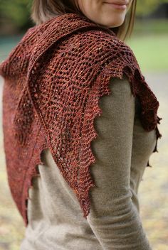 a woman wearing a red knitted shawl in the fall with leaves on it