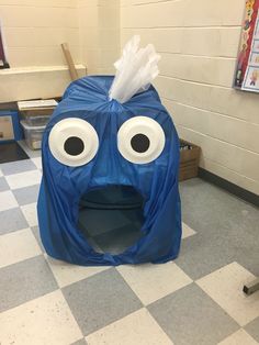 an inflatable blue box with googly eyes and a tissue paper on top