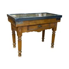 an old wooden table with a glass top on it's legs and two drawers