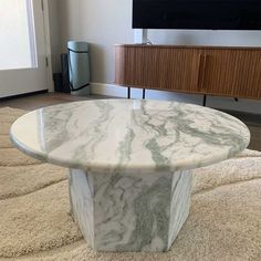 a white marble coffee table sitting on top of a rug in front of a tv