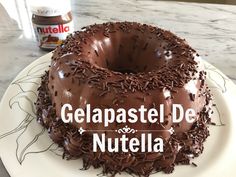 a chocolate cake sitting on top of a white plate next to a bottle of nutella