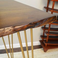 a close up of a wooden table with hair pins on the legs and a chair in the background