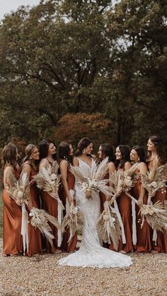 a group of women standing next to each other wearing dresses and holding feathers in their hands